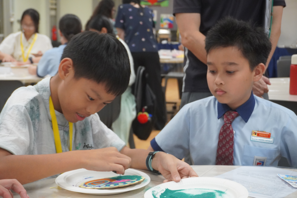 Two boys carefully applying paint to paper plates during an arts and crafts activity.